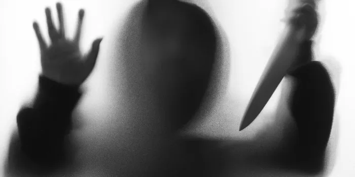 shadow blur of horror man in jacket with hood hold the knife to stabbed and right hand touches the glassdangerous man behind the frosted glassmystery manblack and white pictureblur picture