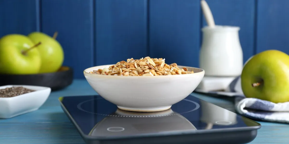 electronic scales with granola on light blue wooden table