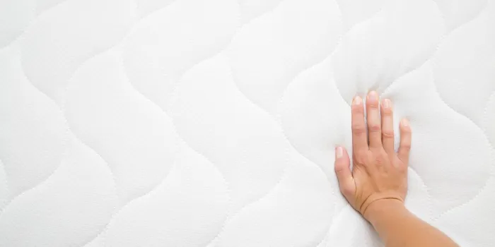 woman's hand pressing on white mattress checking hardness and softness choice of the best type and quality point of view shot copy space empty place for text or logo top view close up