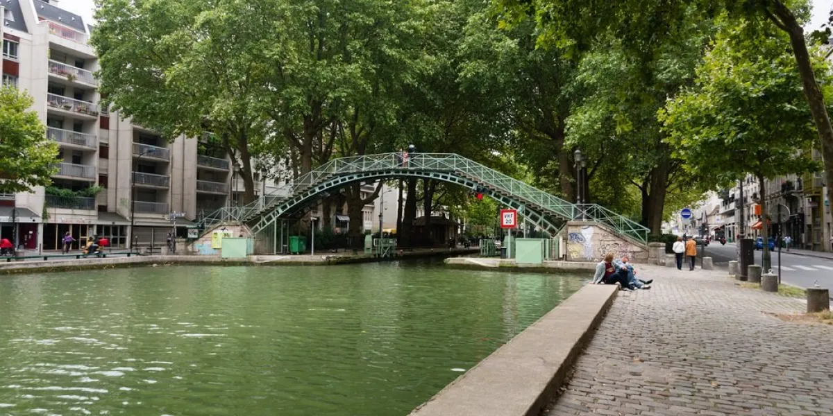 paris, france - july 29, 2014  bridge of the saint-martin canal in paris, france it connects the canal d’ourcq to the seine river people are resting and walking on the banks along the canal