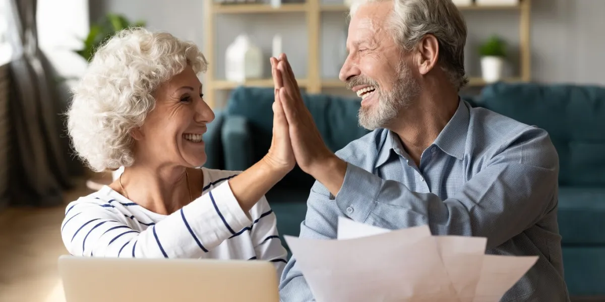 excited older couple giving high five, mature family celebrating success, checking or paying domestic bills, planning budget, smiling mature man holding financial documents, reading good news