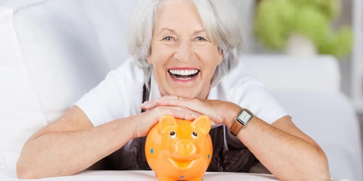 lachende seniorin mit ihrem sparschwein