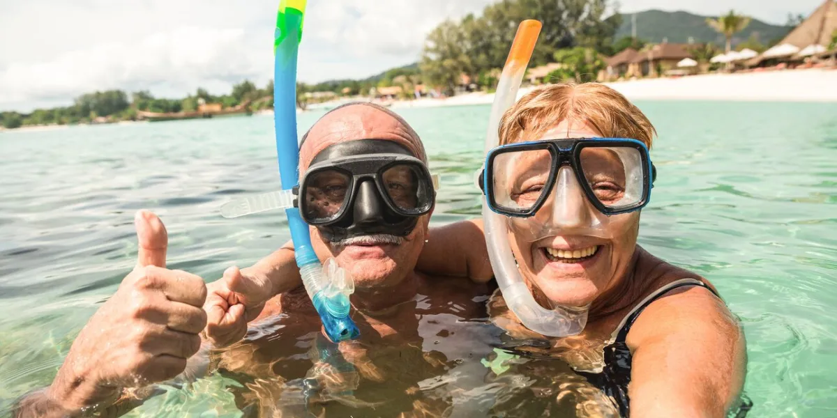 senior happy couple taking selfie in tropical sea excursion with water camera - boat trip snorkeling in exotic scenarios - active retired elderly and fun concept around the world - warm bright filter