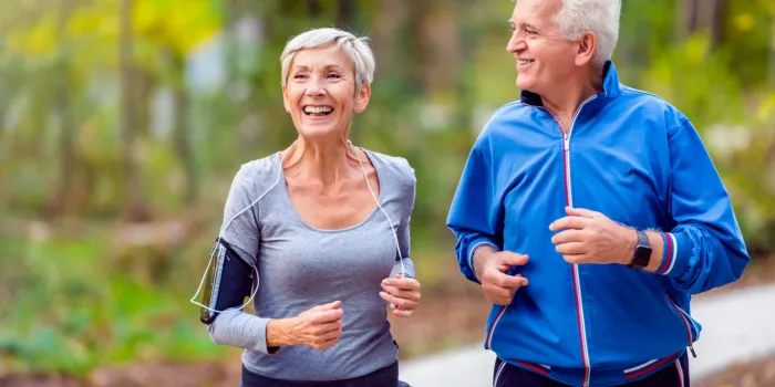 senior active couple running, walking and talking in the park healthy lifestyle