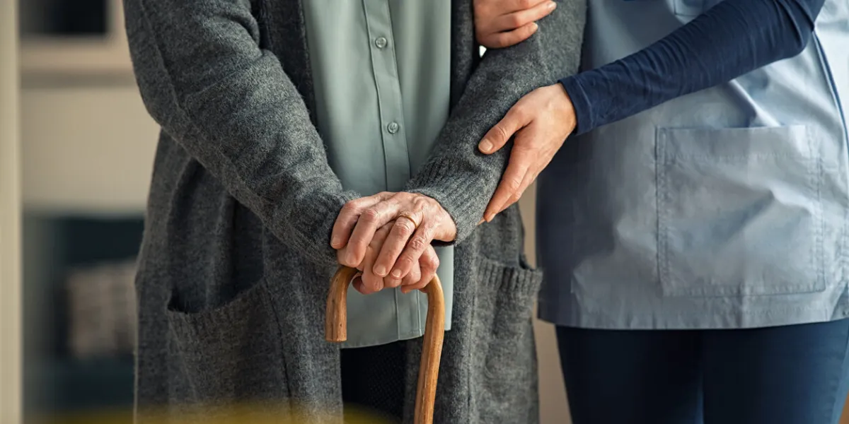 close up hands of caregiver doctor helping old woman at private clinic close up of hands of nurse holding a senior patient with walking stick elder woman using walking cane at nursing home with nurse holding hand for support