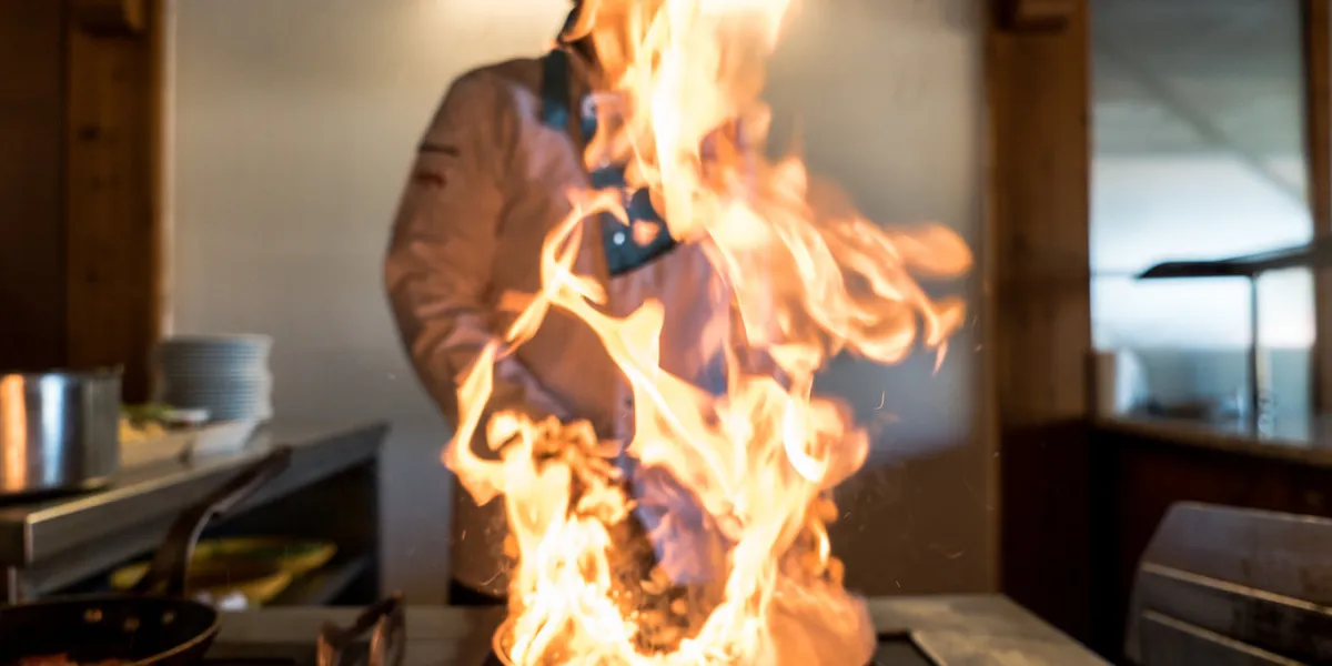 flames bursting from a pan inside a restaurant kitchen