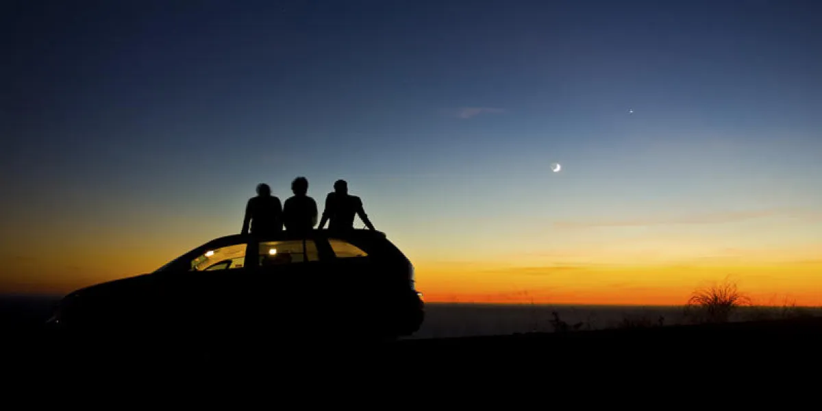 deux personnes assis sur une voiture pendant le coucher du soleil