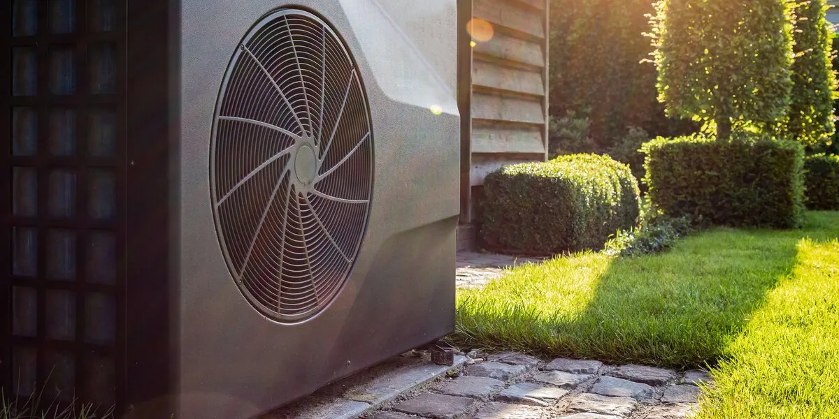 close-up of black full inverter heat pump outside in the garden, near wooden pool house on a sunny day lens flare on the image