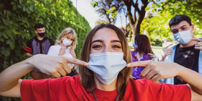 group of teenagers posing showing their protective face masks during covid-19 coronavirus epidemic spread