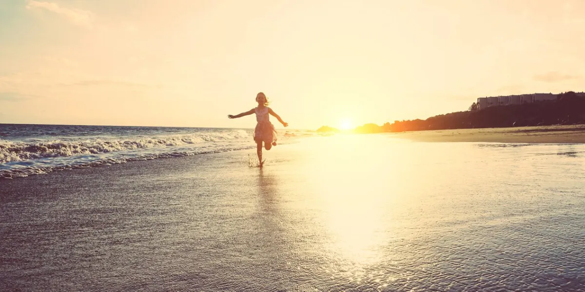 happy little girl running inside water on the beach at sunset - kid having fun in holiday vacation - youth, lifestyle and happiness concept - vintage filter - focus on silhouette