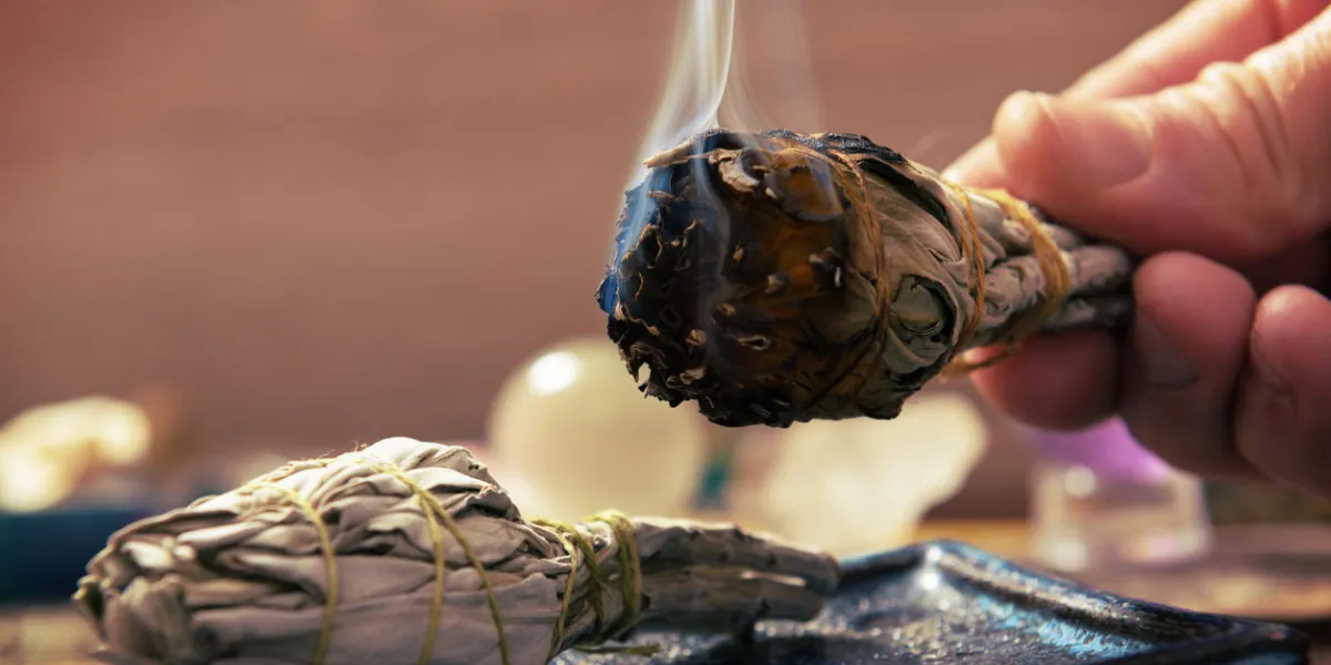 main de l'homme avec de l'encens de sauge blanche naturelle brûlante