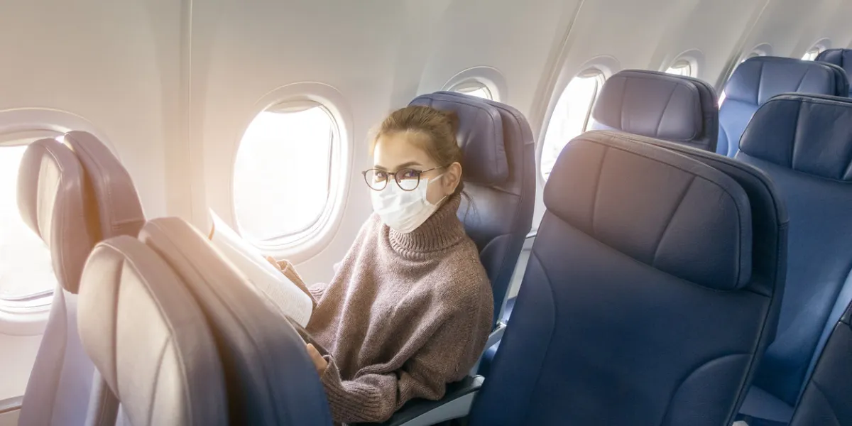 a young woman wearing face mask is traveling on airplane , new normal travel after covid-19 pandemic concept