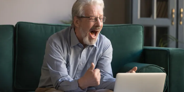 happy excited old elderly man winner excited by reading good news looking at laptop, overjoyed senior mature grandfather watching game online celebrating goal bid bet win great result victory concept