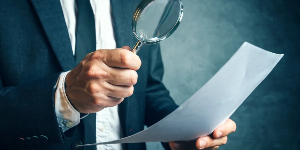 tax inspector investigating financial documents through magnifying glass, forensic accounting or financial forensics, inspecting offshore company financial papers, documents and reports