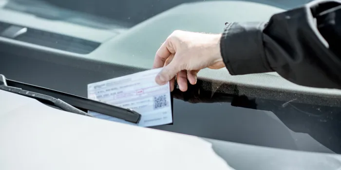 policeman putting fine for improper parking on the windshield of the car, close-up view