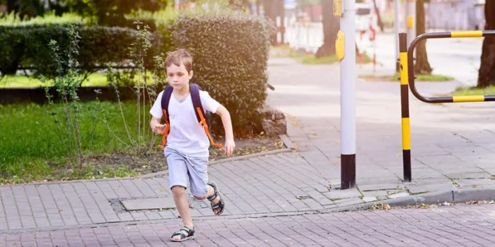 petit 7 ans écolier en attente de feu vert vêtu de blanc t-shirt et shorts sac à dos bleu