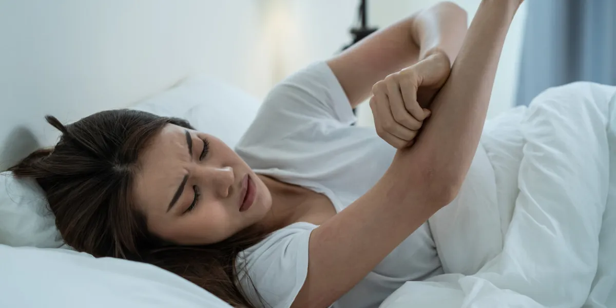 asian young woman scratch hand feel suffer from allergy while sleeping beautiful attractive girl lying on bed in bedroom suffering from itching arm skin allergic reaction to insect bites, dermatitis