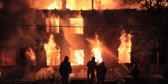 silhouettes of firefighters on on burning house background