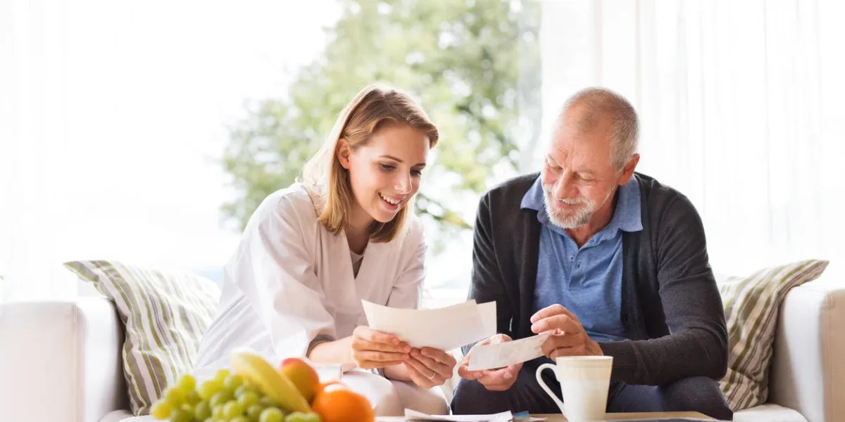 health visitor and a senior man during home visit a female nurse or a doctor discussing test results
