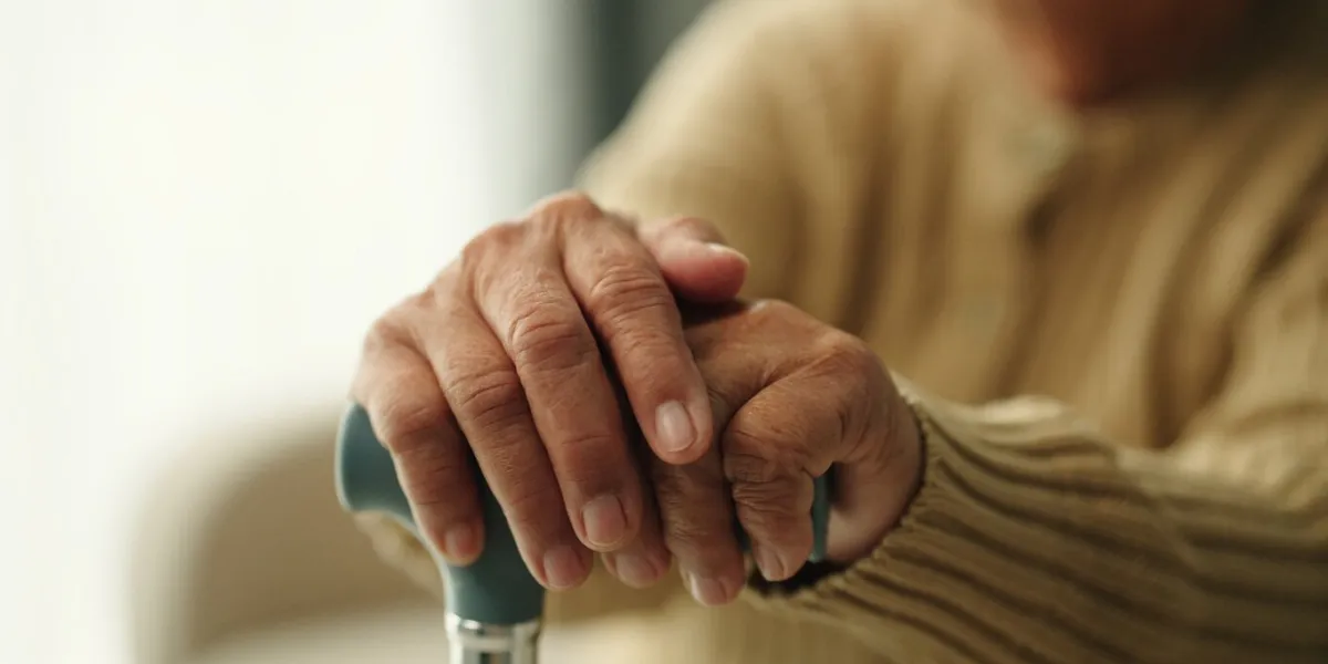 close-up hand of elderly using walking stick while sitting on sofa