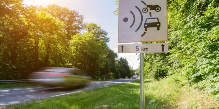 speed limit speed camera sign with cars driving too fast