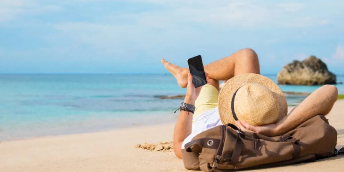 guy with smartphone lying on the beach unrecognisable young male using smartphone while relaxing at seaside