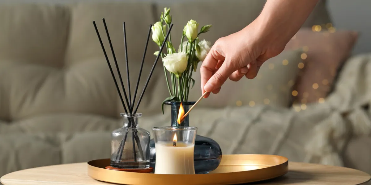woman lighting candle at wooden table in living room, closeup