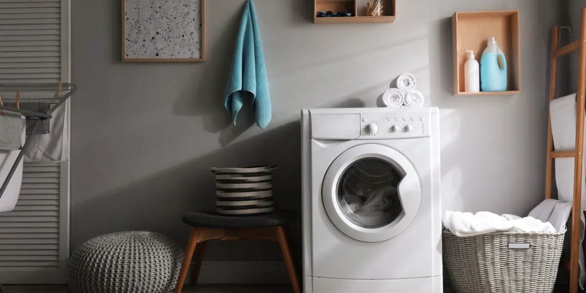 laundry room interior with modern washing machine near light wall