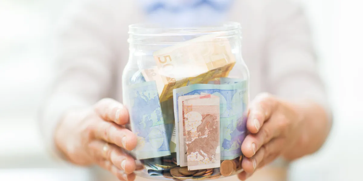 savings, money, annuity insurance, retirement and people concept - close up of senior woman hands holding money in glass jar