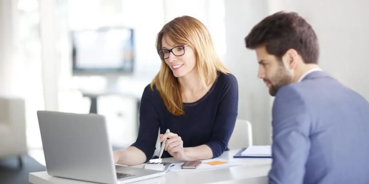 portrait de femme d'affaires de conseiller en investissement assis au bureau en face de l'ordinateur et de consulter un jeune homme professionnel