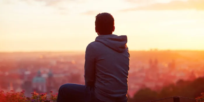 young man is looking at the sunrise