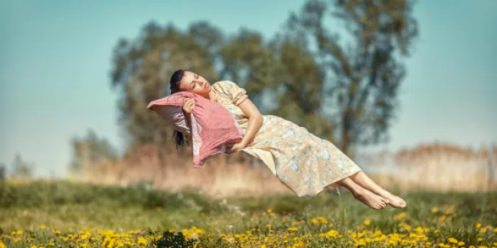 fille plane et dort sur un oreiller sur une belle prairie