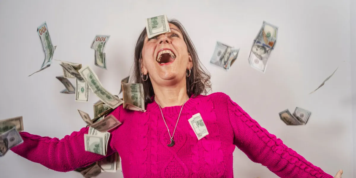 woman celebrates under a rain of 100 dollar bills