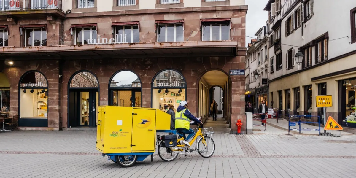 strasbourg  la poste courier delivery riding electric bike with cargo trailer containing letters and parcel