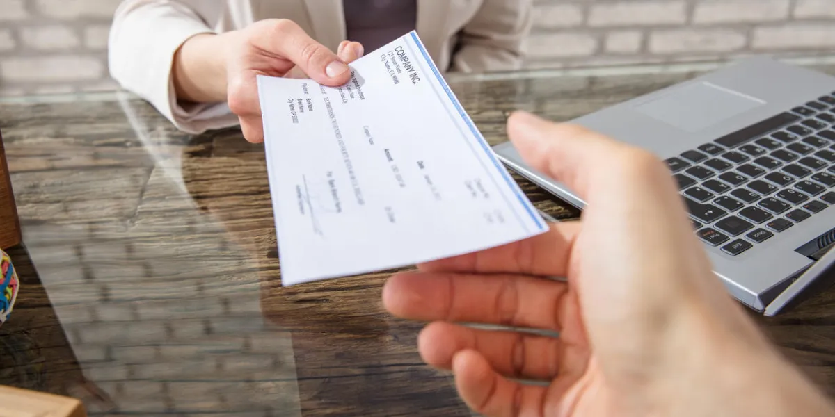 close-up of a business woman giving cheque to her colleague at workplace in office