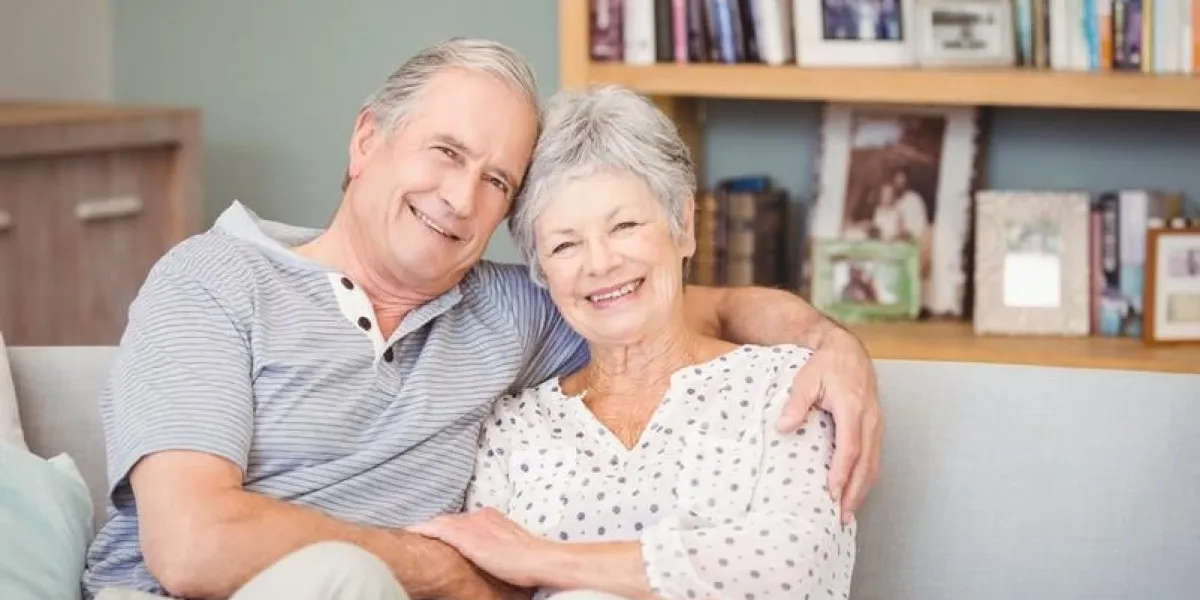 portrait of happy senior couple sitting on sofa at home