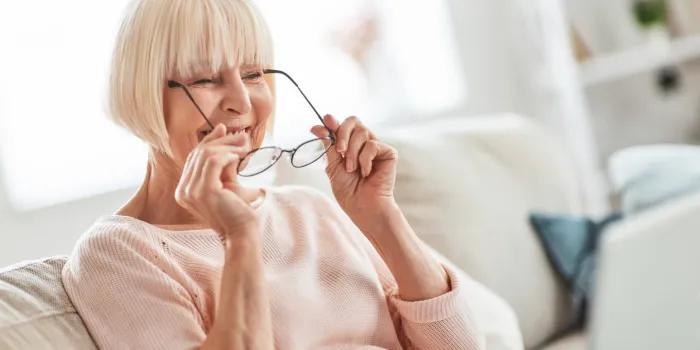 beautiful senior woman putting on her eyewear while relaxing on the couch at home