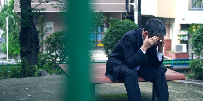depressed asian businessman sitting on a bench