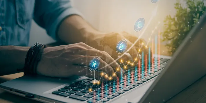 casual businessman using and typing laptop computer with color currency stock or forex market bar chart and line graph and world map financial economy and business growth concept in vintage tone