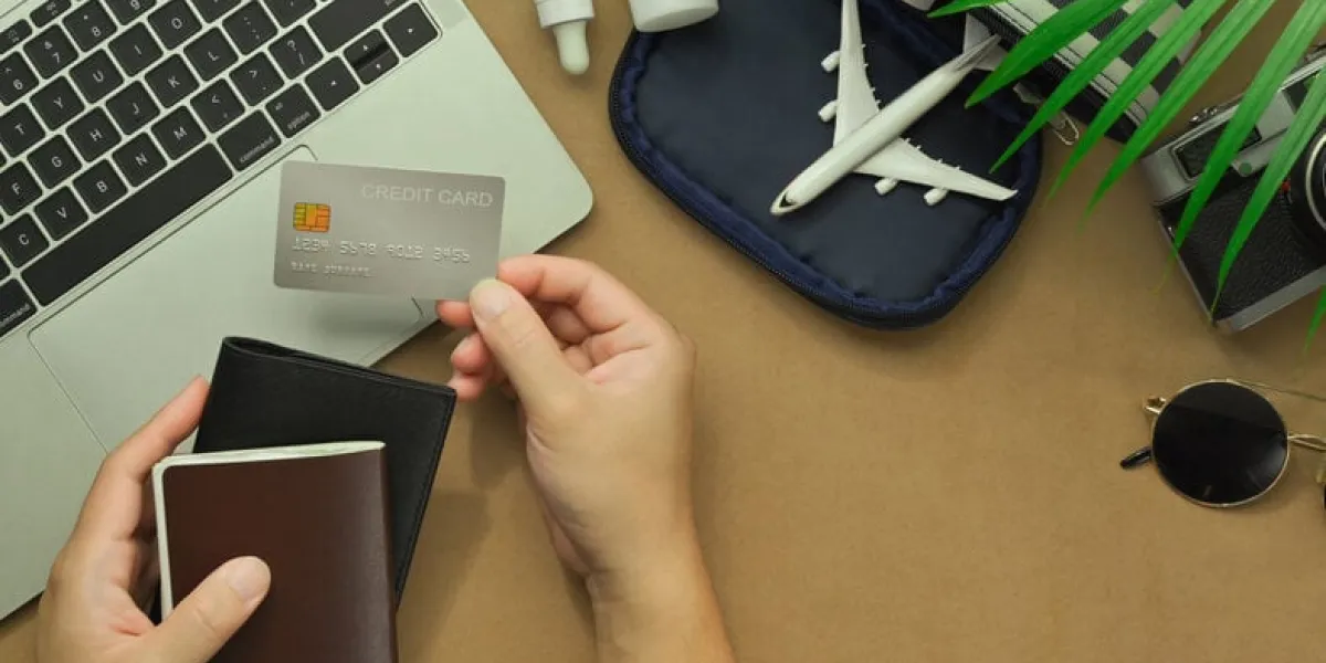 top view of woman hand holding credit card with travel accessories and passport on desk traveling concepts