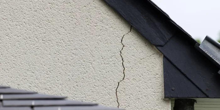 major crack in the plaster of a house wall just under the slate roof