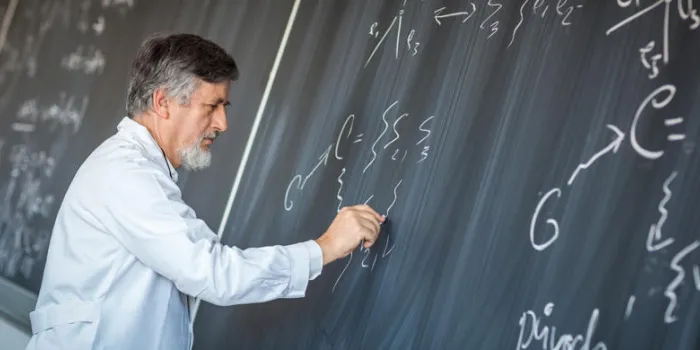 senior chemistry professor writing on the board while having a chalk and blackboard lecture (shallow dof, color toned image)