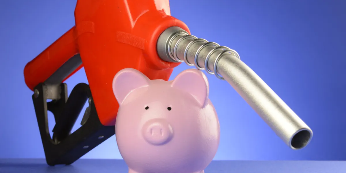 a concept of saving money at the gas pumps using a piggy bank and red fuel pump over a blue background
