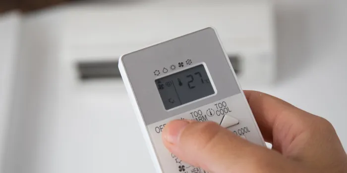 hand turning on an air conditioning control, where 27 degrees are seen on the screen, as recommended by the new regulations of the spanish government for summer