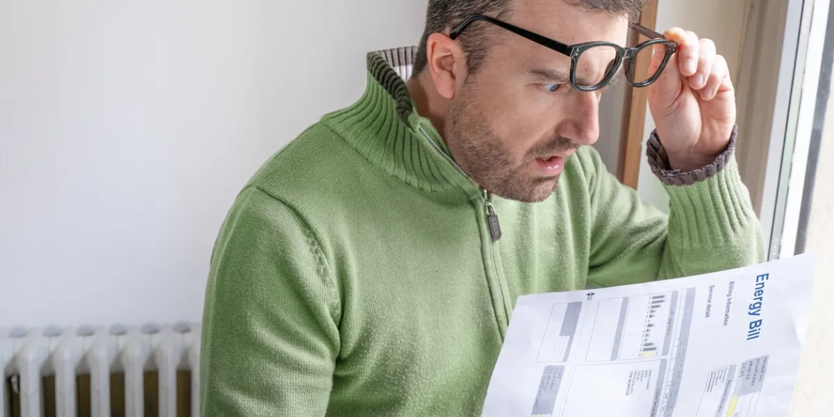 shocked man reading some bills energy expenses on sofa living room