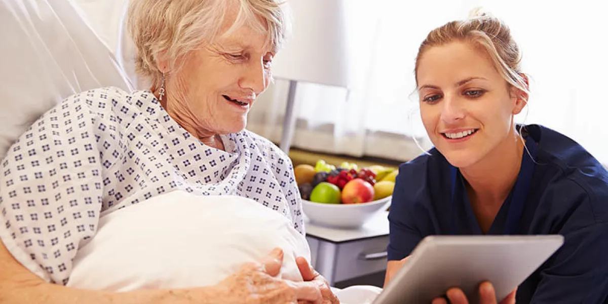 nurse talking to senior female patient in hospital bed