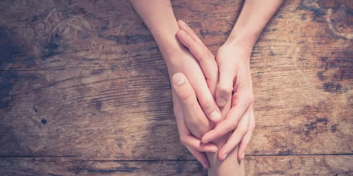 close up on a man and a woman holding hands at a wooden table