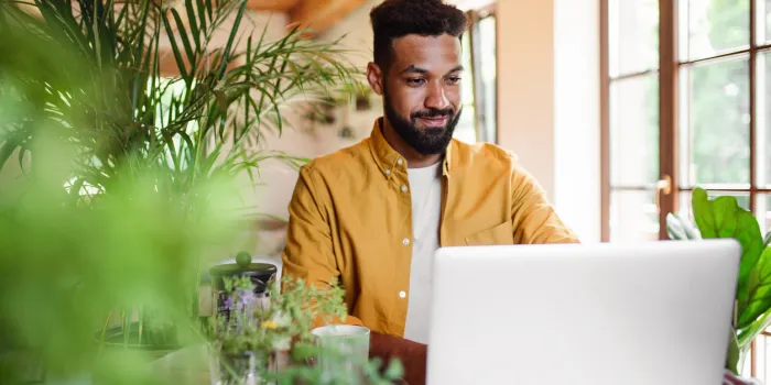 a young man with laptop and coffee working indoors, home office concept