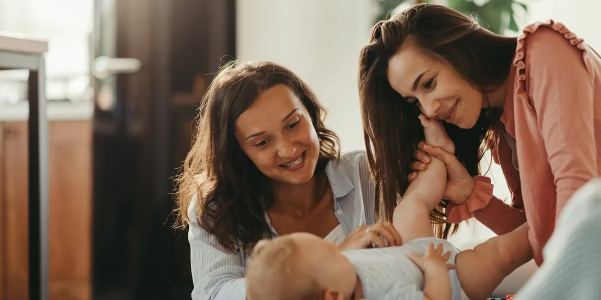 loving lesbian couple playing with their baby while spending time together at home
