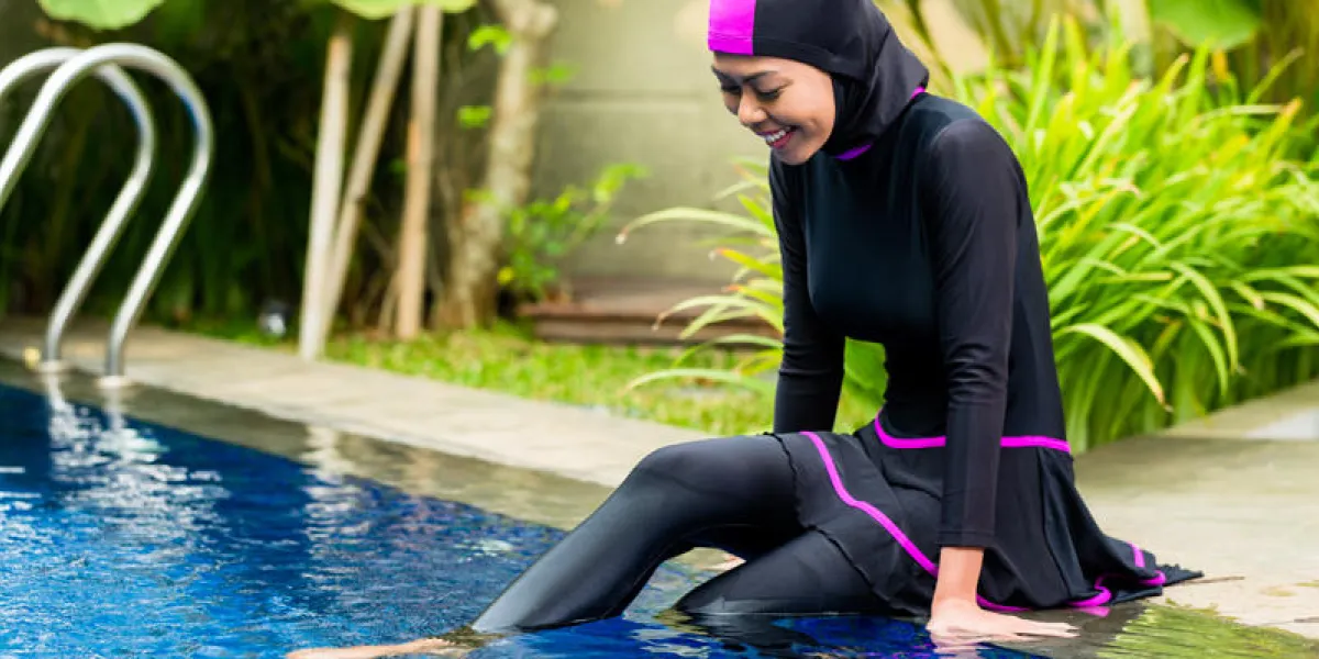 femme musulmane ou une fille assise à la piscine dans un jardin tropical portant des maillots de bain halal burkini